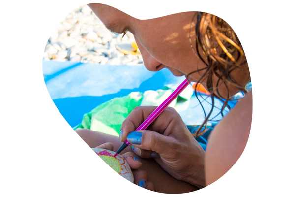 Vrouw op het strand, een steen beschilderend